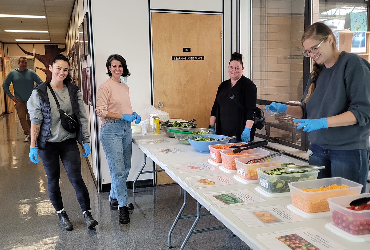 Volunteers and teachers standing by a salad bar table