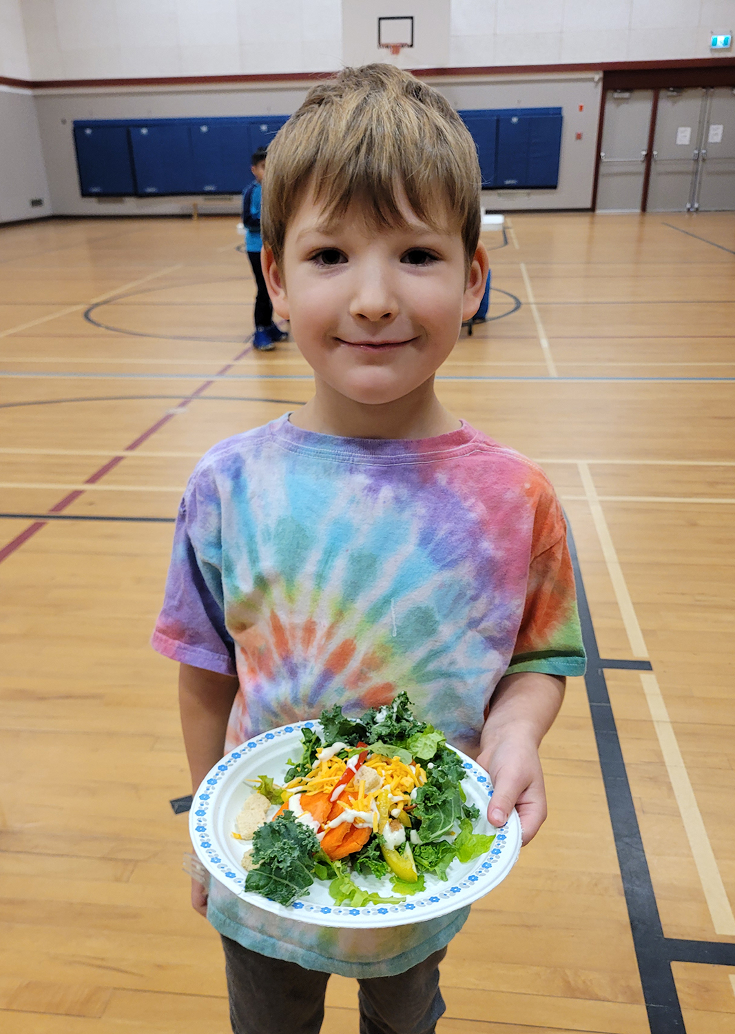Young boy holding plate of salad